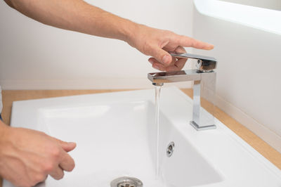 Men's hands turn on the water in the tap