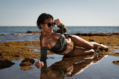 Full length of woman lying down on beach against sky