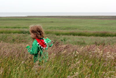 Girl on field by sea against sky