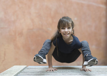 Portrait of smiling girl balancing on hands against wall