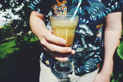 Midsection of man holding drink in glass