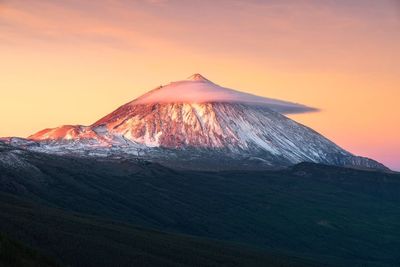 Low angle view of volcanic mountain against sky during sunset