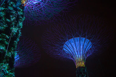 Low angle view of illuminated trees against sky at night