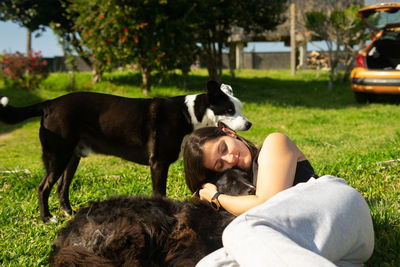 Smiling woman with eyes closed embracing dog lying on grass