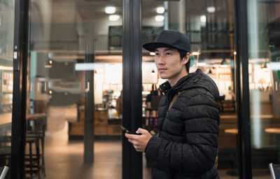 Young man using mobile phone in illuminated building