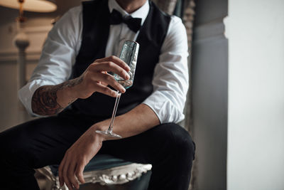 Midsection of man holding champagne flute