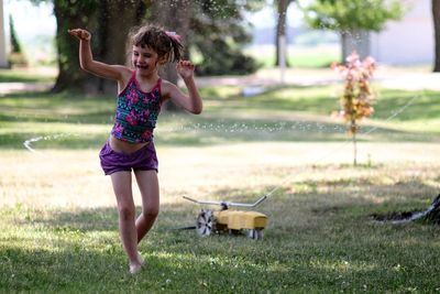 Full length of woman with arms raised on grass