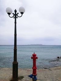 Street light by sea against sky