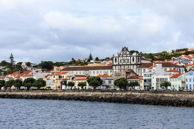 Buildings by river against sky in city