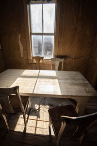 Empty chairs and table against window