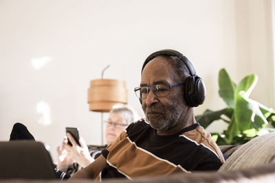 Senior man with headphones using laptop at home