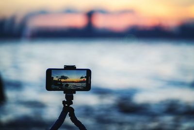 Close-up of camera on pole against sky at sunset