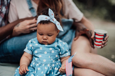 Midsection of mother and daughter sitting outdoors