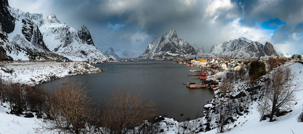 Scenic view of snowcapped townscape and mountains against sky during winter