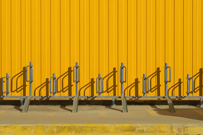 Bicycle parking near a bright yellow profiled metal wall, fence or warehouse idea, background 