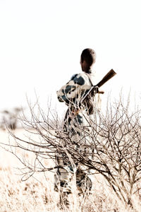 Rear view of man standing on field against clear sky