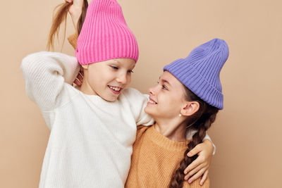 Sibling wearing knit hat against beige background