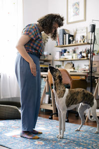 Side view of woman giving obedience training to dog at home
