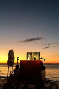 Deck chairs on beach against sky during sunset