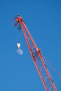 Low angle view of crane against clear blue sky