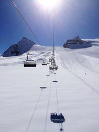 Ski lift over snow covered field against sky