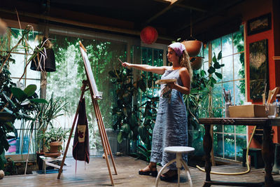 Full length of woman looking at easel