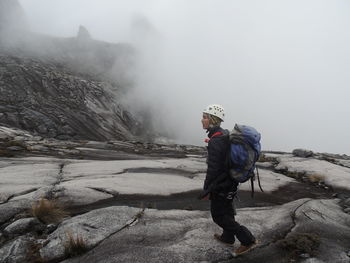 Side view of female hiker on rocky mountain during foggy weather