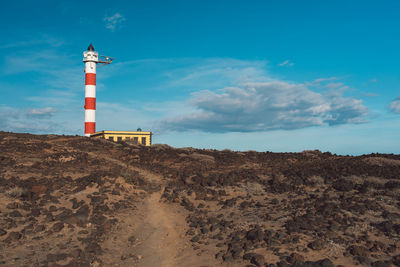 Lighthouse on street amidst buildings against sky