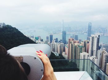 Cropped image of woman looking cityscape through coin-operated binoculars