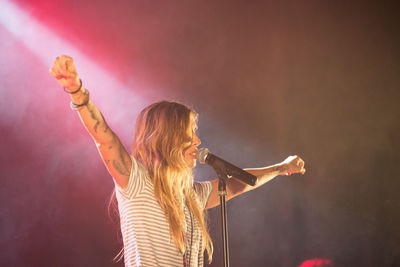 Rear view of woman with arms raised standing in background