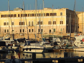 Boats moored at harbor against buildings in city