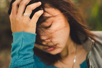 Close-up portrait of woman covering face with hand