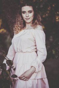 Portrait of smiling young woman standing by plant