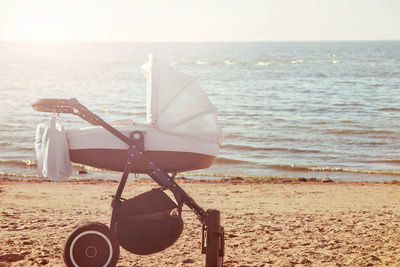 Baby stroller on beach against sea