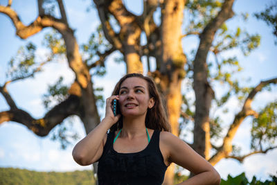 Portrait of smiling young woman standing by tree