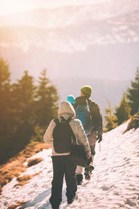 Rear view of people walking on snow covered mountain