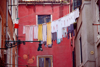 Vintage style picture of an old alley with laundry lines in venice, italy colorful pink red house 