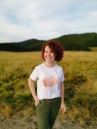 Portrait of smiling young woman standing on field