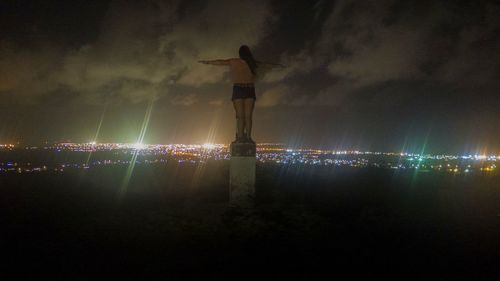 Silhouette woman standing on beach against sky at night