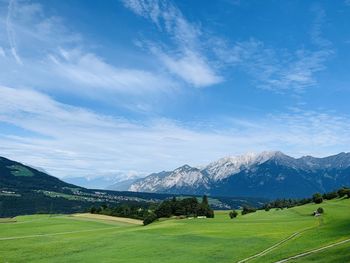 Scenic view of field and mountains against blue sky