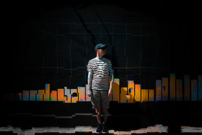 Full length of woman standing against wall at night