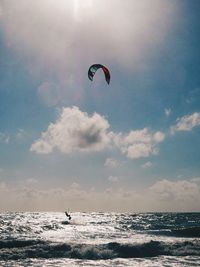 Person paragliding over sea against sky