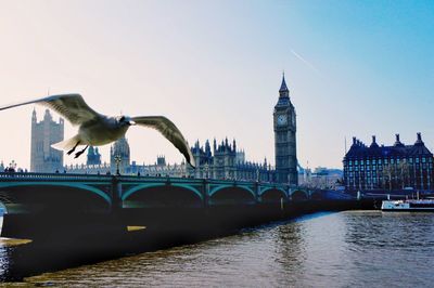 Bridge over river in city against clear sky