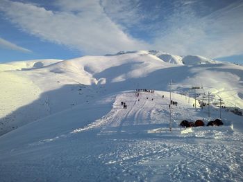 People skiing on snowcapped mountain against sky