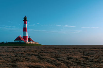 Lighthouse on field against sky