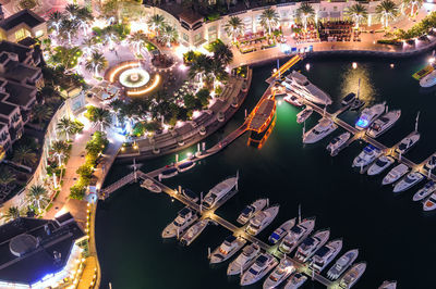Aerial view of illuminated buildings by boats moored at harbor in canal