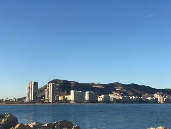 Sea by buildings against clear blue sky