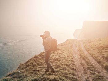 Man standing on shore by sea against sky