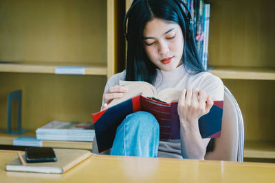 Young woman looking away while sitting on table