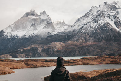 Rear view of person on snowcapped mountain against sky